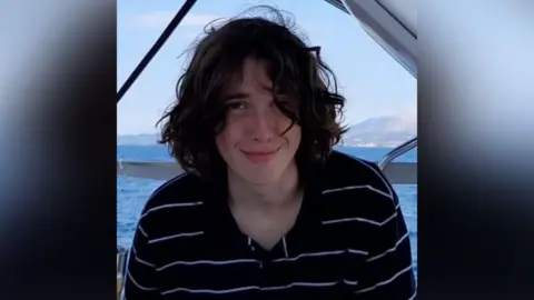 Family handout A young man with long hair, smiling at the camera. The sea and mountains can be seen in the background.