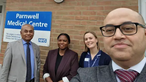 Dr Laliwala and Partners Mohsin Laliwala, a man wearing a grey suit, standing next to Mercy Oviasogie, who is a woman in a purple blazer. Lauren Collins wears a blue dress and Nabeel Laliwala is a man with glasses.