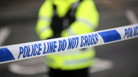 BBC Generic shot of a police cordon with an officer standing in high-vis in the background, out of focus