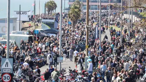 Stuart Woodward/BBC Western Esplanade in Southend, with thousands of people walking along both sides of the road and hundreds of motorbikes parked up in a line.
