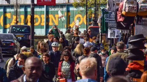 Getty Images Image from 2021 showing crowds walking down Camden High Street, with the green and yellow Camden Lock bridge graffiti behind them