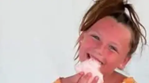 Family Handout A child eating candy floss and smiling.