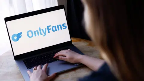 Stock image of woman looking at OnlyFans website on a laptop computer
