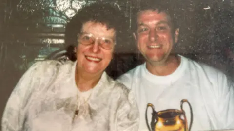 Family handout Nancy, with glasses and wavy brunette hair, smiles next to her son Maurice