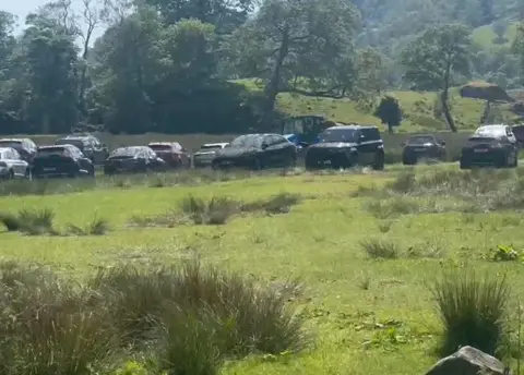 Supplied Cars parked in a field dirty with splashes of slurry.