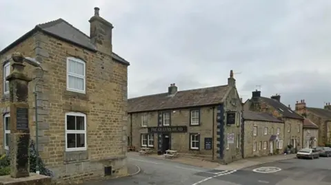 A view of the North Yorkshire village of Kirkby Malzeard showing a pub and various stone buildings 