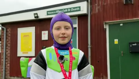 Luna pictured in her buzz lightyear suit. She is looking directly at the cameral and is also wearing a red lanyard around her neck.