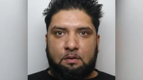 National Crime Agency A custody photo of a man with short spiked hair and a trimmed beard, looking directly at the camera against a plain background.