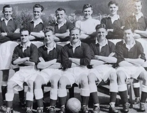 Peebles Rovers A football team with dark shirts and white shorts line up in a black and white photograph