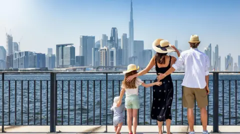 A family of four looking across the water at the Dubai skyline