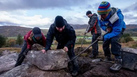 LITTLEHOUSE MEDIA A group of people moving heavy rocks on the mountain side