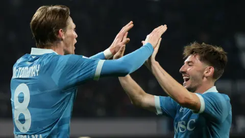A match picture of McTominay celebrating by giving a "big ten" clap to Billy Gilmour, both are wearing their Napoli strips.