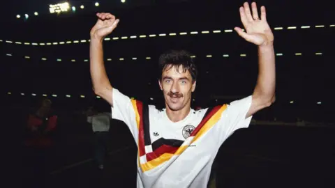 Getty Images Ian Rush, wearing a Germany shirt, holds his hands aloft and smiles after Wales beat them in a Euros qualifier in 1991