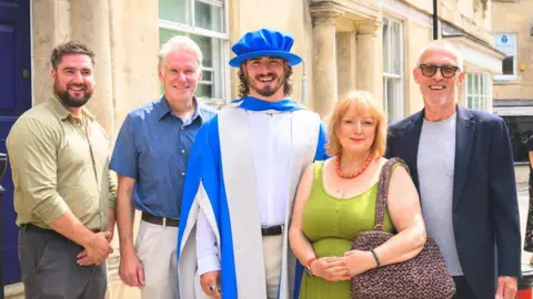 Eddie Ilic Ilic in the centre in his graduation gown and cap with his family around him. 