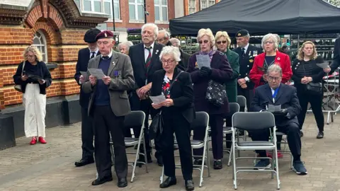 A crowd of people gathered to take part in a VE Day service in Epsom