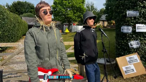 Lily-May Symonds/BBC Liam and Noel Gallagher, as scarecrows, with guitar and microphone