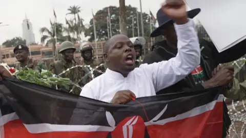 A protester holds a Kenyan flag during a demonstration in front of Kenya's Parliament on June 25 2026. 