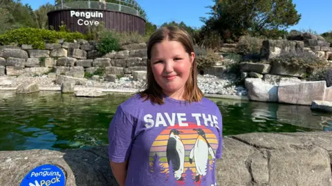 Ellie next to the pool in a 'Save the penguins' shirt.