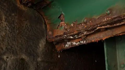 Gateshead Council A rusty section of a corner of the parapet of the Tyne Bridge. The green paint is flaking around rusty brown rivets.