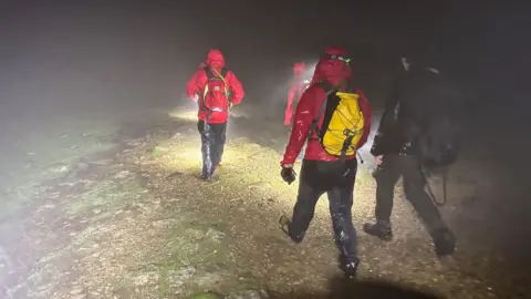 Four mountain rescue volunteers walking to Helvellyn in the torrential rain