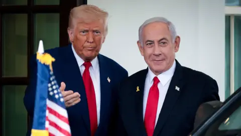 President Donald Trump speaks as Israeli Prime Minister Benjamin Netanyahu waves and smiles following a meeting in the White House, in Washington in April. 

Both men wear blue suits and red ties. 