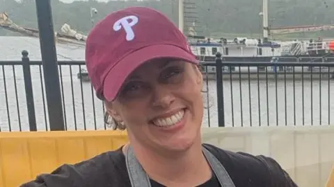 Emily McCorkell pictured with a red cap and apron standing outside at Derry Quay 