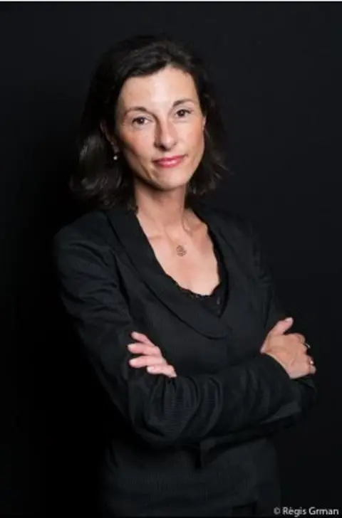 Anne-Laure Domenichini Anne-Laure Domenichini is pictured against a dark background. She has dark hair, dark dress and is standing with her arms crossed 