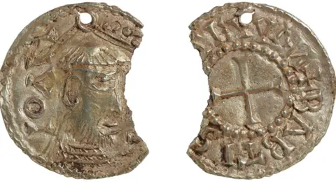Two views of a gold coin which has a chunk representing perhaps a fifth of its diameter missing out of its side. The left view shows a profile of a man with a beard and tonsure. The right side has a cross in its middle and around it is written St John the Baptist in Latin. John, Baptist and Evangelist