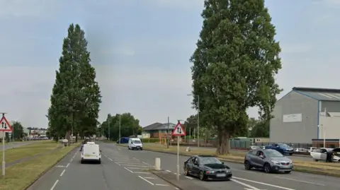 Google A main   roadworthy  with vehicles travelling successful  some  direction. A mates  of roadworthy  signs and ample  trees enactment     each   broadside  of the road.