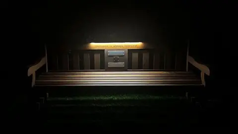 Legend on the Bench A bench is lit up at night by a light strip, which is illuminating the words "Someone is always listening" on the back support. There are plaques and a QR code beneath it.