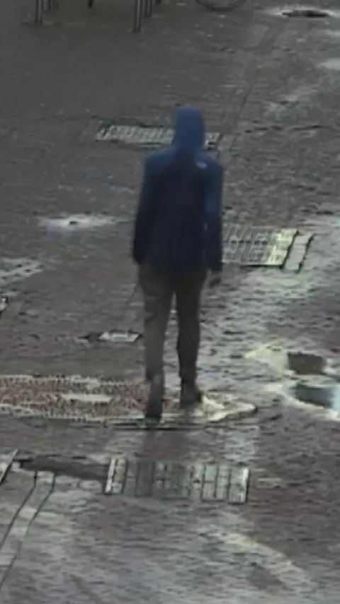 CCTV of a man in a dark hooded jacket, walking down an Edinburgh street
