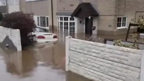 Supplied A front drive with flood water covering the wheels of a white car