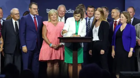 Getty Images Iowa Governor Kim Reynolds signs the bill into law in June 2023