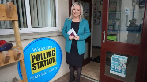 PA Blonde haired woman with a blue jacket and black dress and tights outside a polling station 