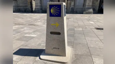 A stone marker stands in Southampton. The St James' Way logo stands at the top of it, with an arrow pointing right in the middle and 647 miles at the bottom.