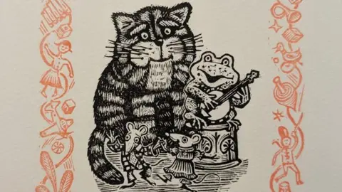 A black and white linocut artwork featuring Bagpuss smiling, some dancing mice and a guitar playing frog