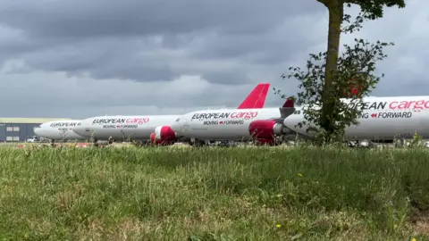 Four European Cargo planes parked at an airport on a cloudy day.