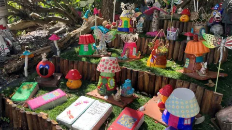 Shariqua Ahmed/BBC Colourful gnomes and other decorative items placed in the theme garden.