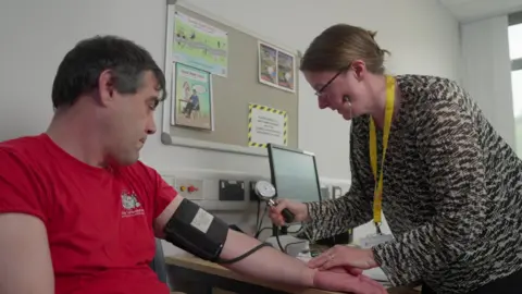 Clear The Fog Tom is having his blood pressure taken by Dr Emma Hall in her clinic.