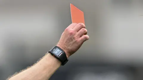 Getty Images A hand holds up a red card. 