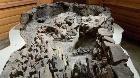 A close-up of the ancient Roman pottery kiln with eroded stone and brick walls, showing a weathered, sunken structure used for high-temperature firing.