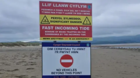 Kevin Gibson Signs on the beach read 'No vehicles beyond this point' and 'fast incoming tide, beware of being trapped on the sandbanks by the incoming tide'.