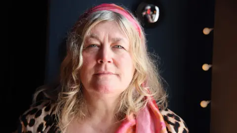 BBC Kellie Sutherland wearing a leopard-print top and pink headscarf