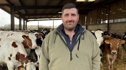 Mike Catley stood in front of his cows on a farm