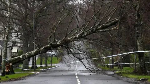 Getty Gambar Jalan perumahan di Helensburgh dengan pohon, diturunkan oleh angin, menghalangi jalan. Adegan telah ditutup dengan pita polisi