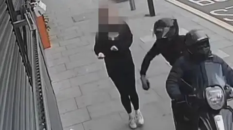 A motorcyclist grabbing a woman's phone on a London street
