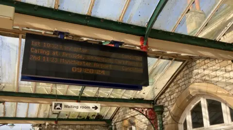 BBC/Jennie Dennett Grange-over-Sands train announcement board saying cancellations