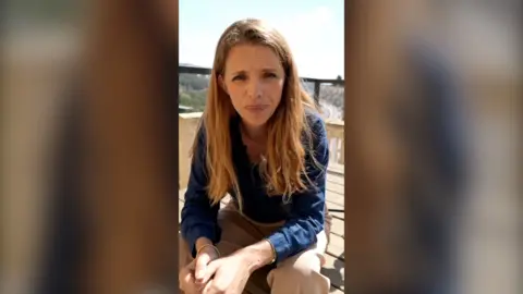 Correspondent Carrie Davies sitting on balcony and wearing navy shirt