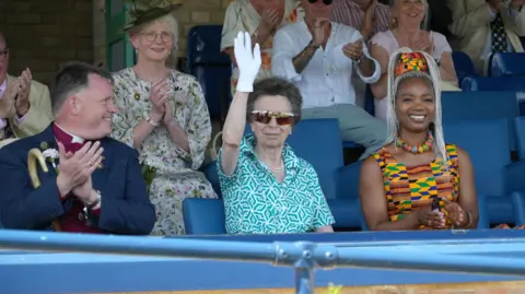 Shaun Whitmore/BBC The Bishop of Norwich, The Princess Royal and Anna Mudeka sitting in a row in a stand at the Royal Norfolk Show.