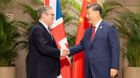 PA Media Keir Starmer and XI Jinping shaking hands in front of the UK and Chinese flags